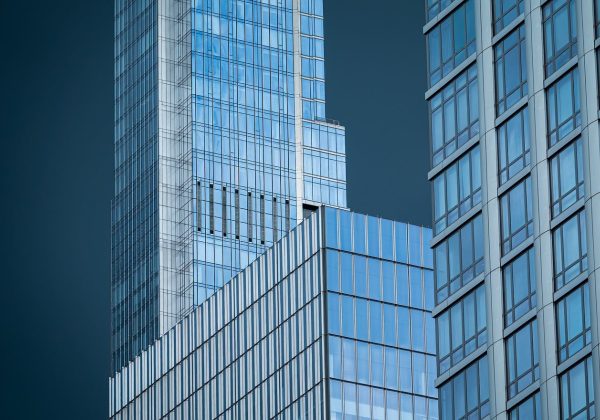 城市街区的高分辨率卫星俯视图，方格状路网与建筑屋顶阴影分明，主干道上可见细小的车辆轮廓，午后光线偏暖